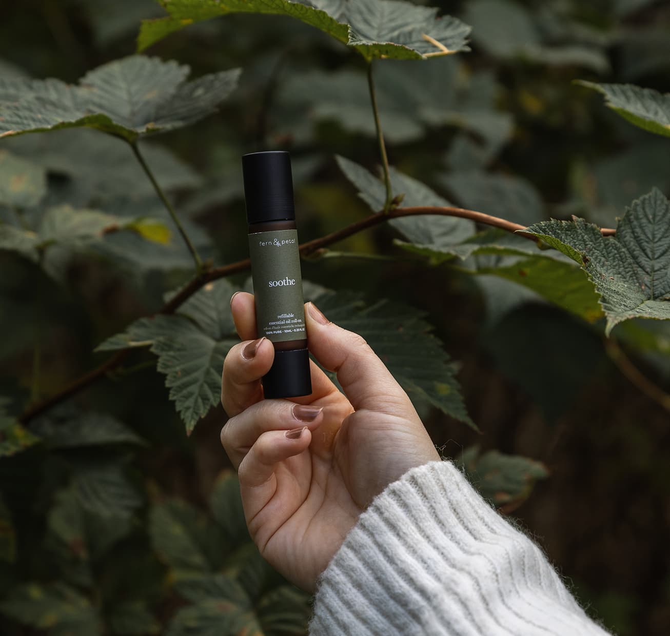A hand holding up a soothe roller against nature