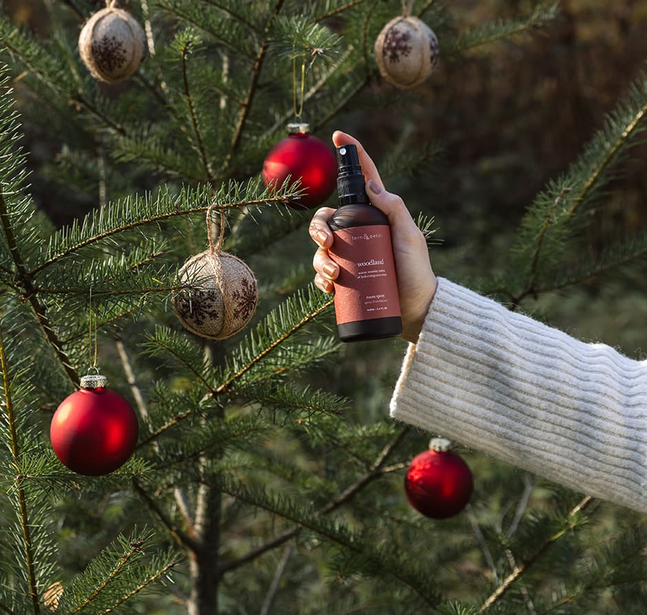 A Woodland Spray held up against a tree with ornaments